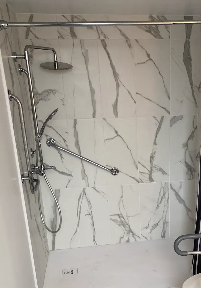 Douche en céramique effet marbre avec barres d'appui et douchette